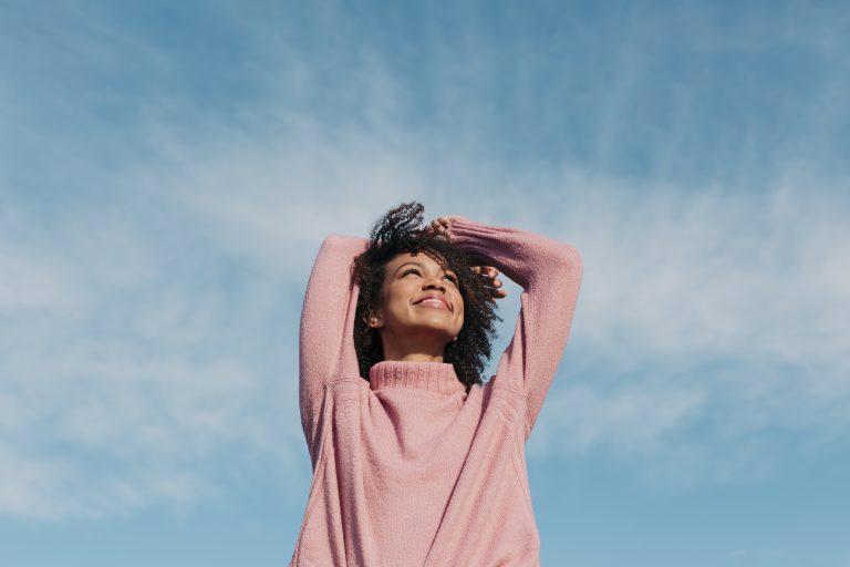 a smiling woman looking at the blue sky