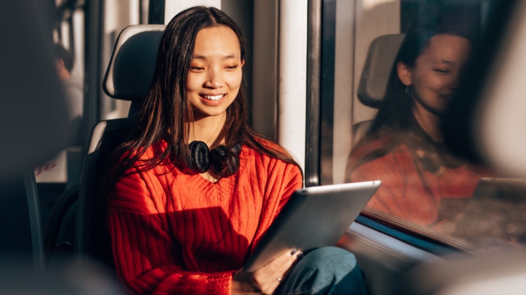 Happy Asian woman sitting in a fast train